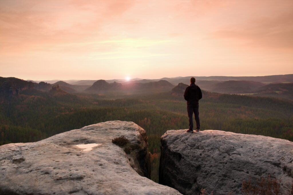 depressed man standing on rock overlooking landscape